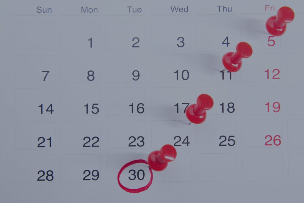 A calendar with red push pins marking dates