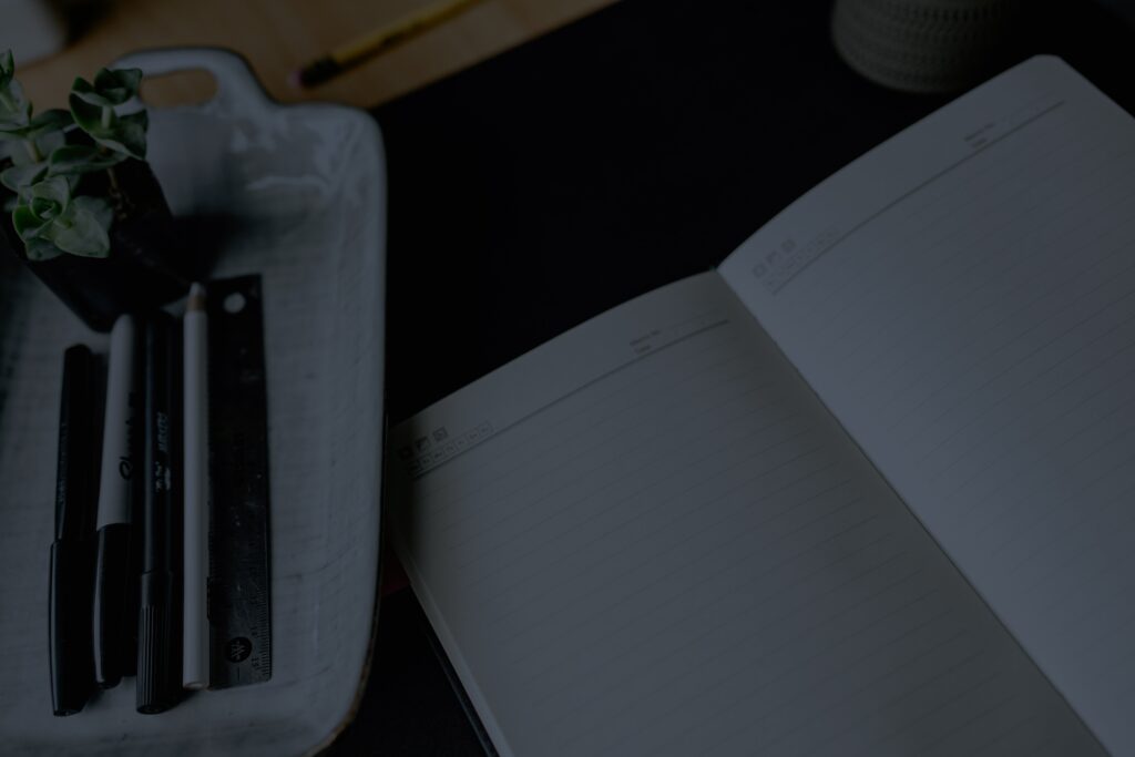 An open notebook and pens on a desk