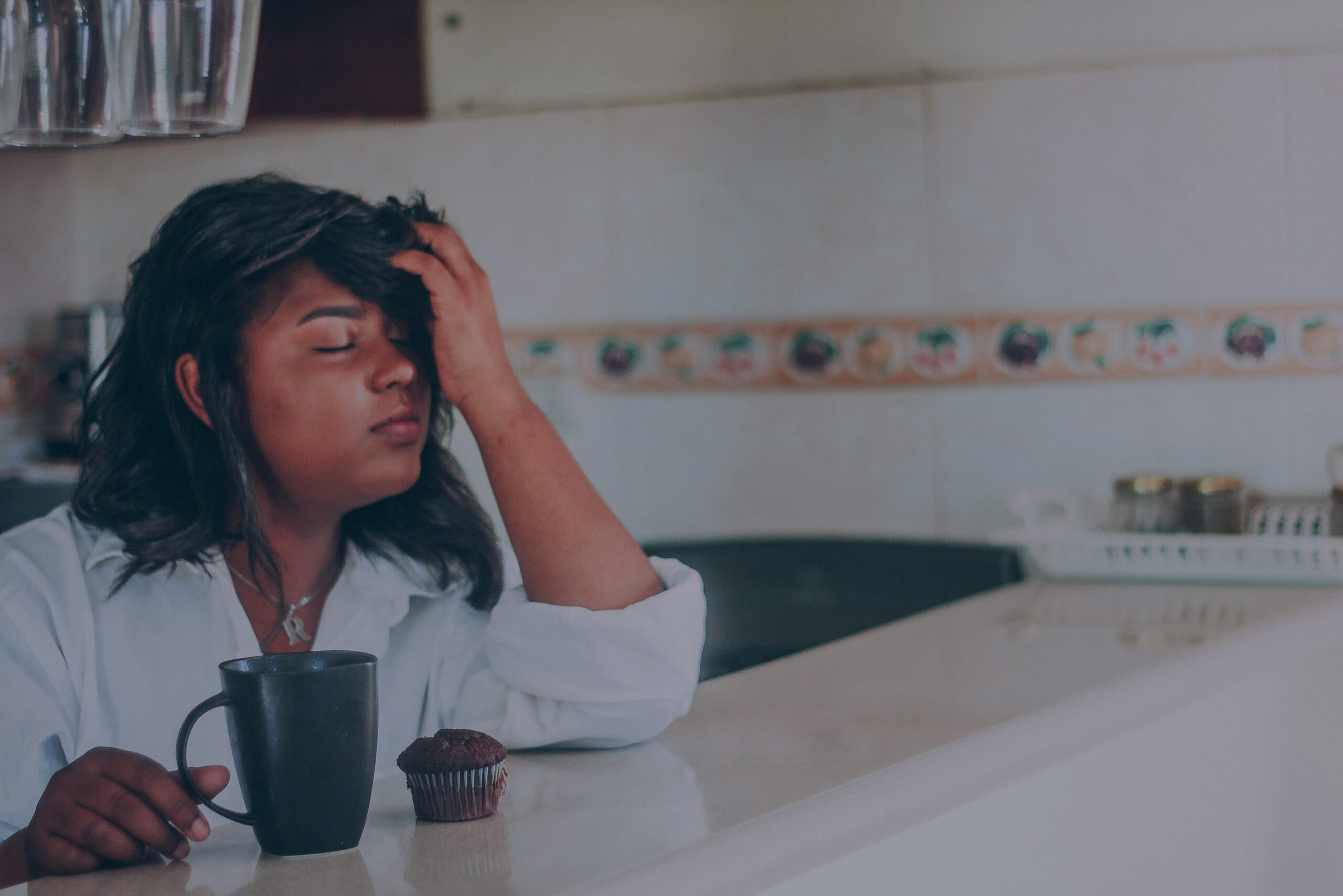 A tired mother moves through her morning kitchen routine despite feeling unwell, reflecting the lack of maternal self-care built into most households.