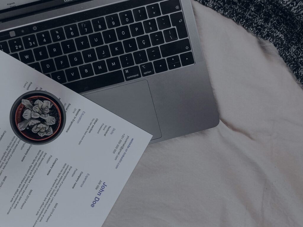 laptop and resume papers on a café table during a job search