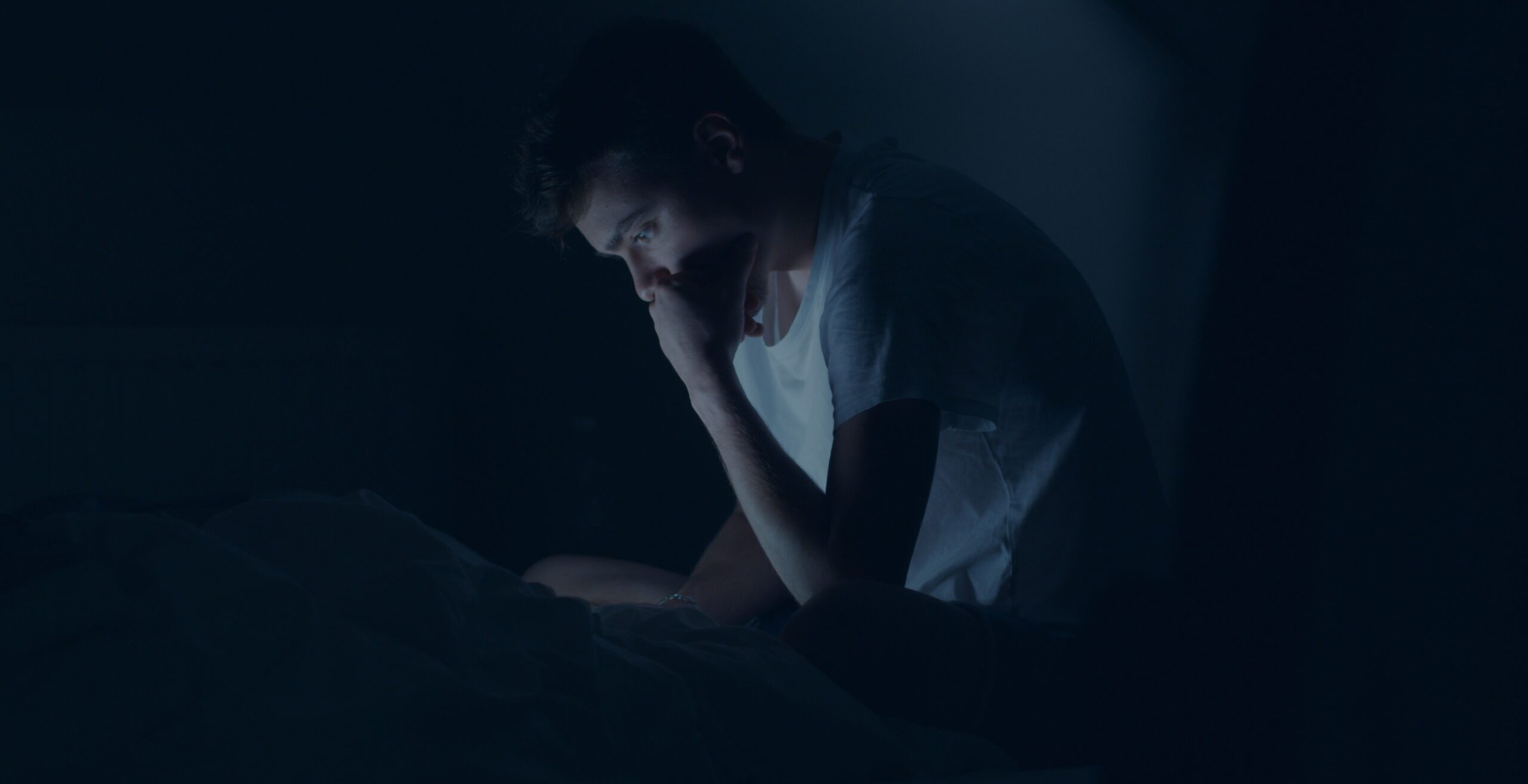 Person lying awake in bed at night, staring at the ceiling, unable to sleep