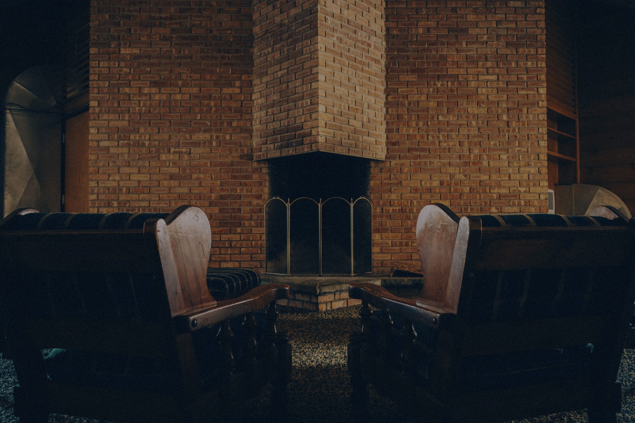 Two church pews facing each other in front of a brick fireplace