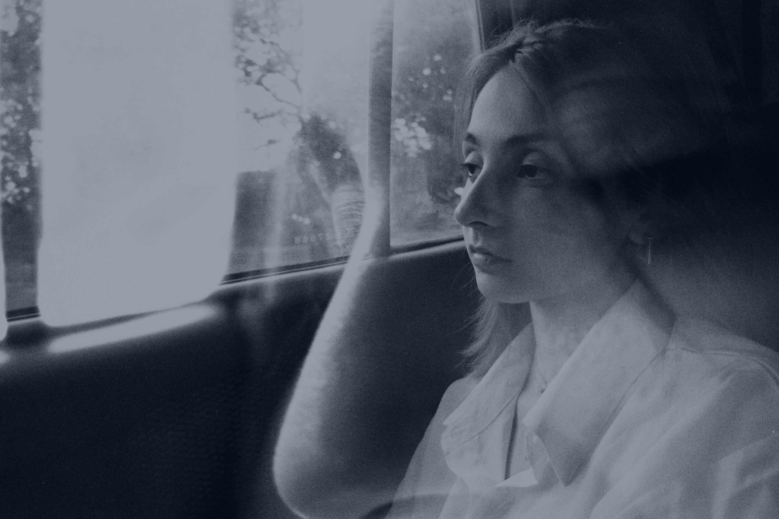 Woman sitting in her car staring blankly out the window, showing signs of burnout and emotional exhaustion